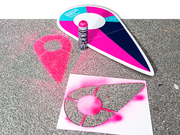 Schablone und Farbdose auf Asphalt, daneben ein aufgesprühtes rosa Marker-Symbol.
